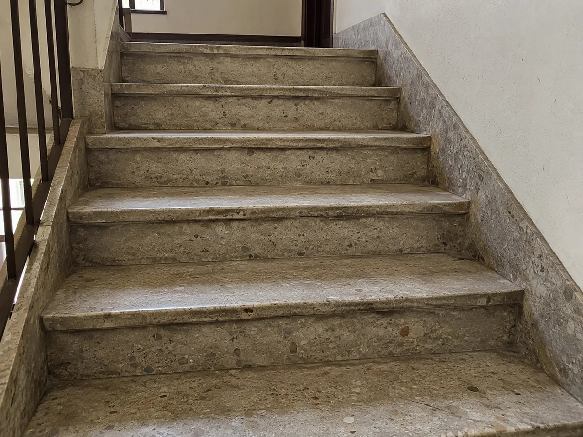 Escalera de terrazo diamantada, con el peldaño y la contrahuella recuperados y brillo uniforme — sin tratar